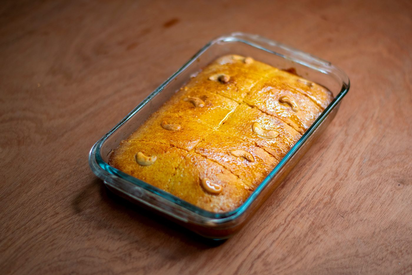 Mawa cake in its baking dish, cut and cooling on a wooden table