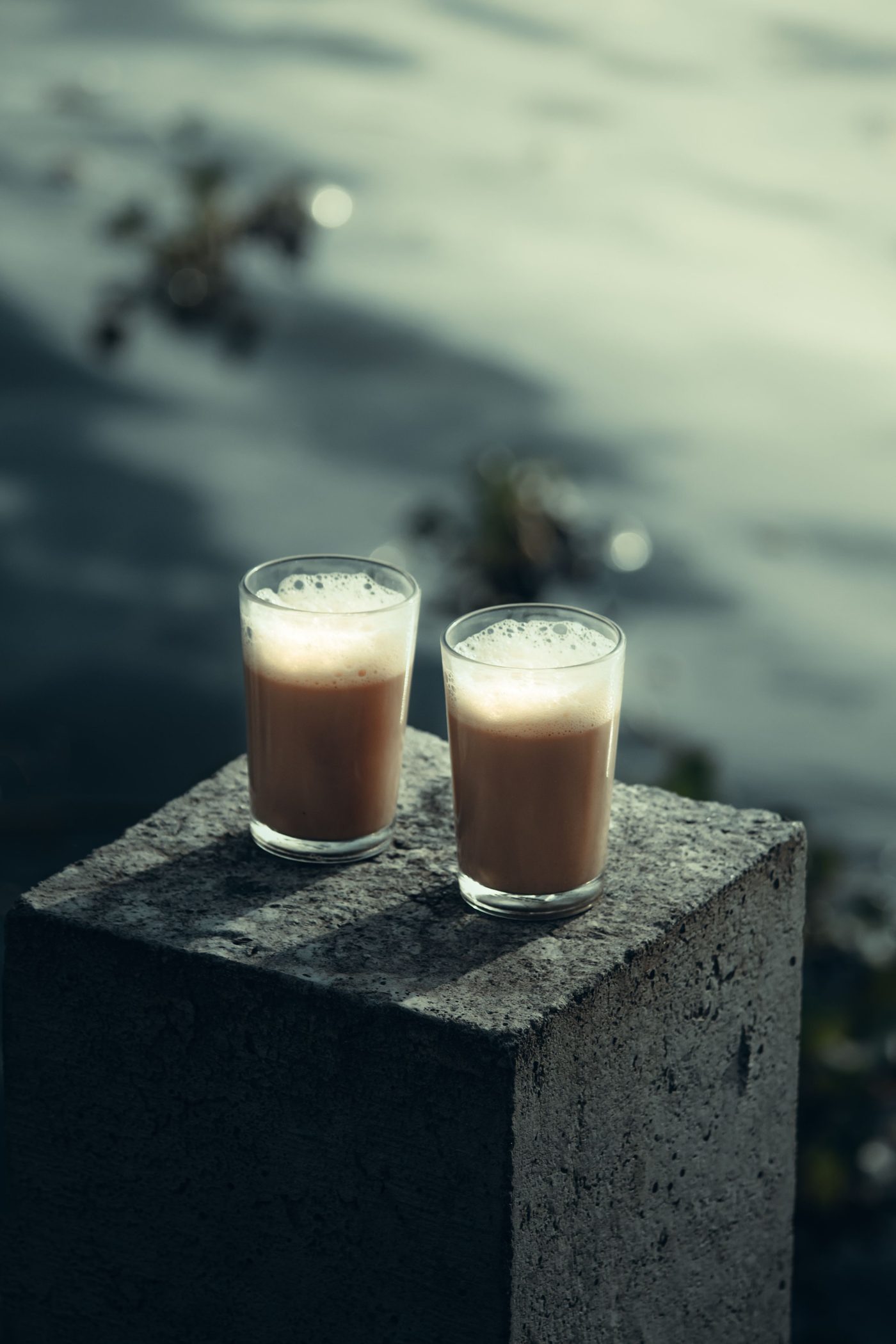 Two cutting chai glasses, hot, resting on a stone ledge